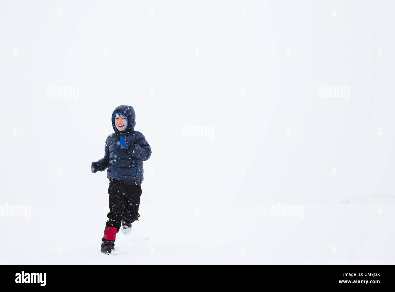 Boy (6-7) running in snow Stock Photo
