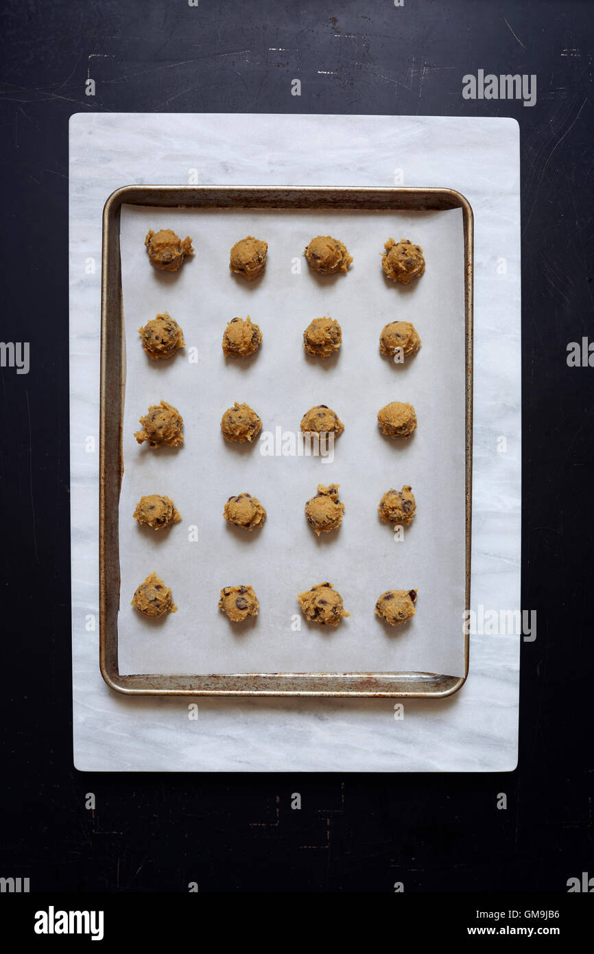 Overhead view of portions of chocolate chip cookie dough on baking sheet Stock Photo