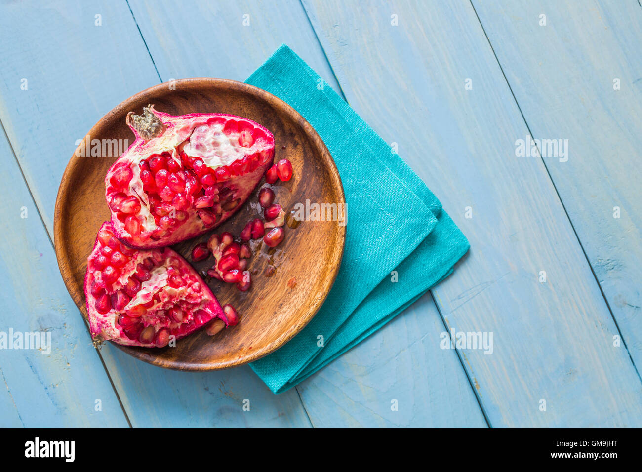 Overhead view of halved pomegranate on wooden plate Stock Photo