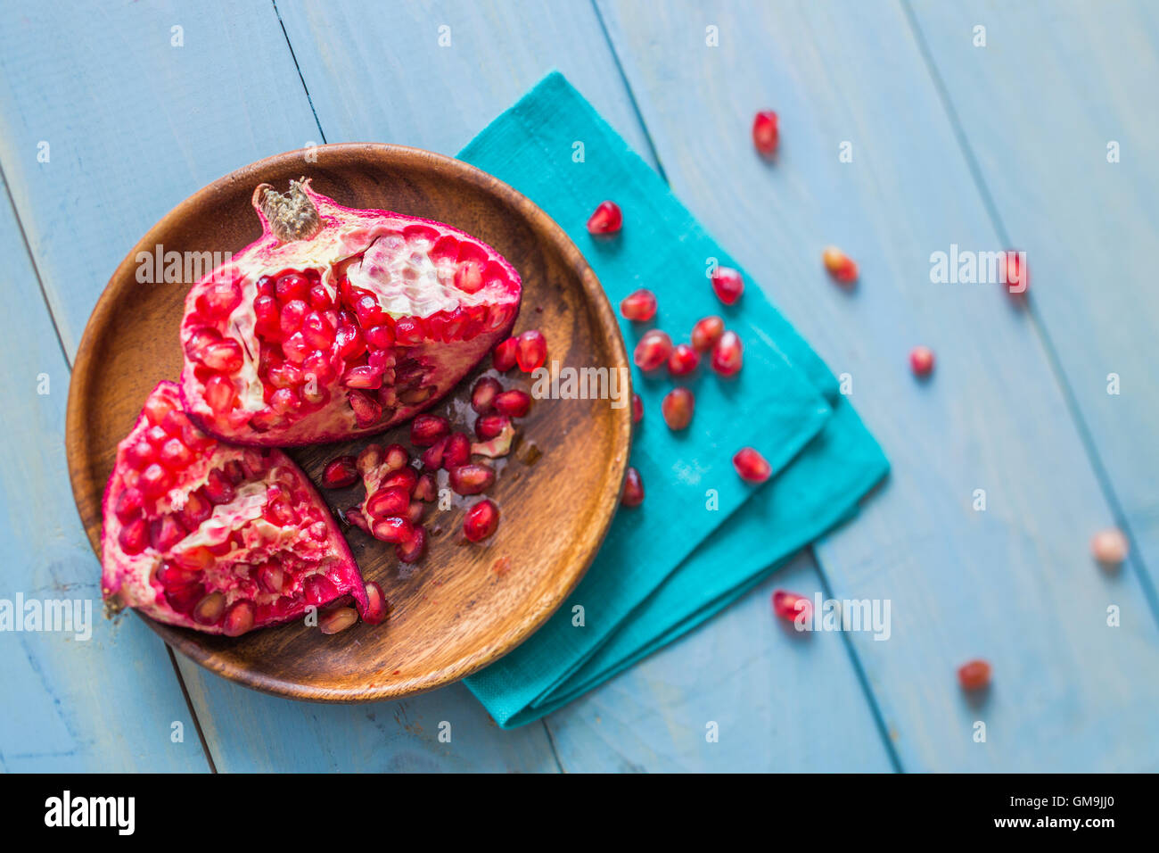 Overhead view of halved pomegranate on wooden plate Stock Photo