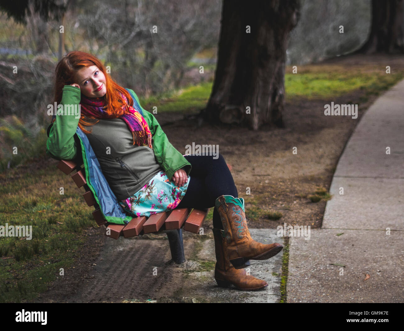 Young woman sitting on bench in park Stock Photo