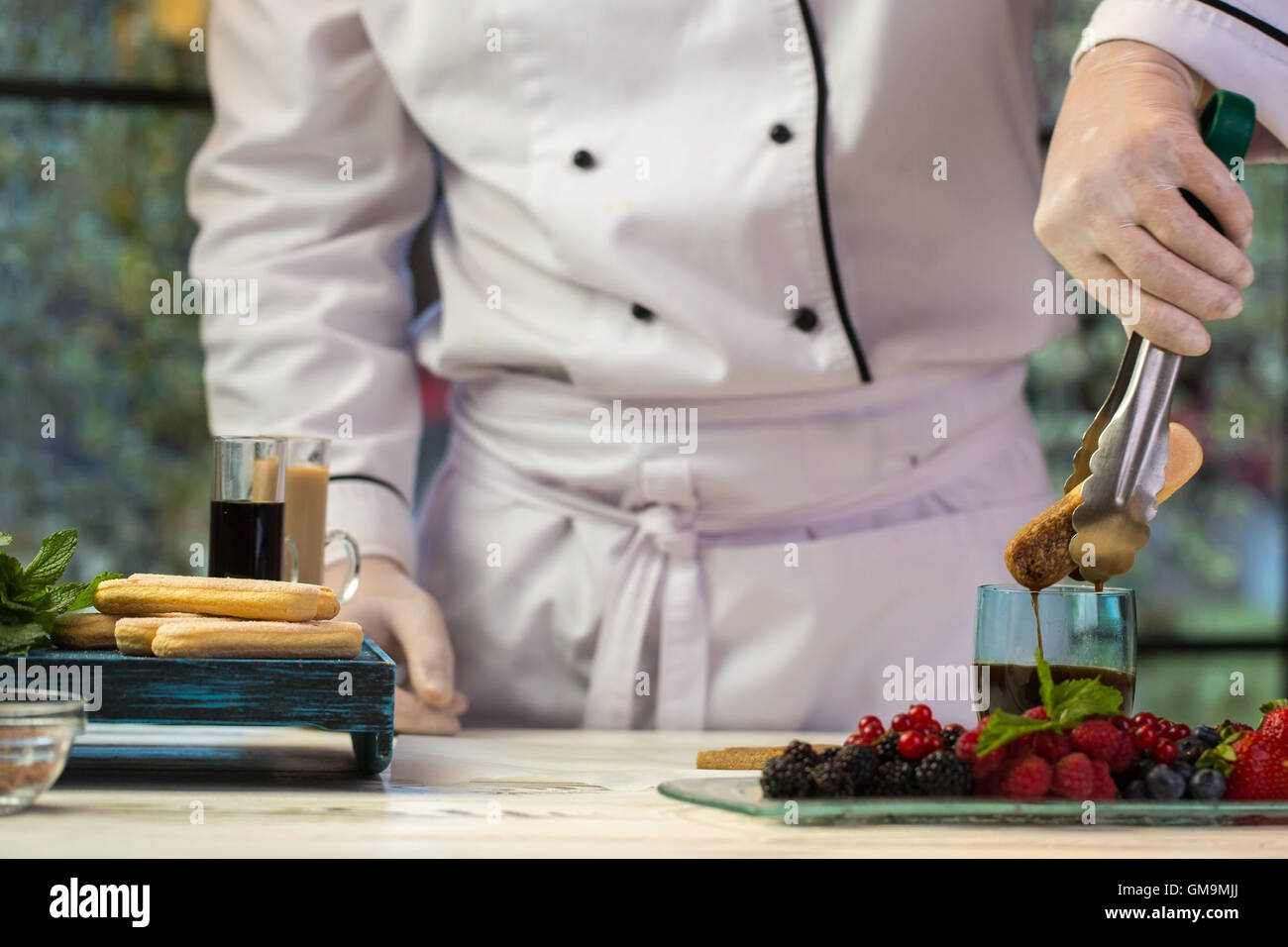 Hand with tongs holding biscuit. Stock Photo