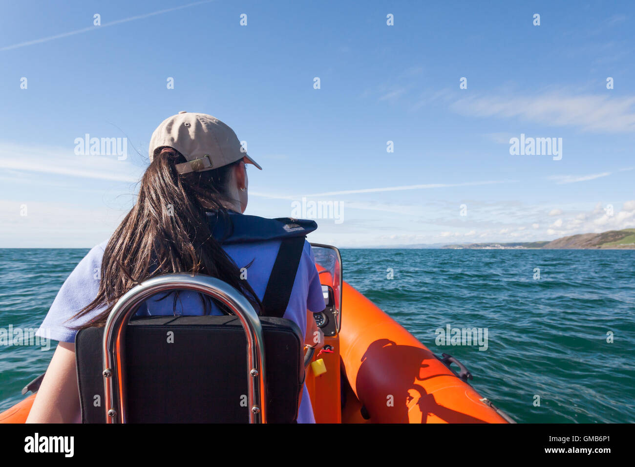 Young girl at the helm of a rib boat on Cardigan Bay Stock Photo