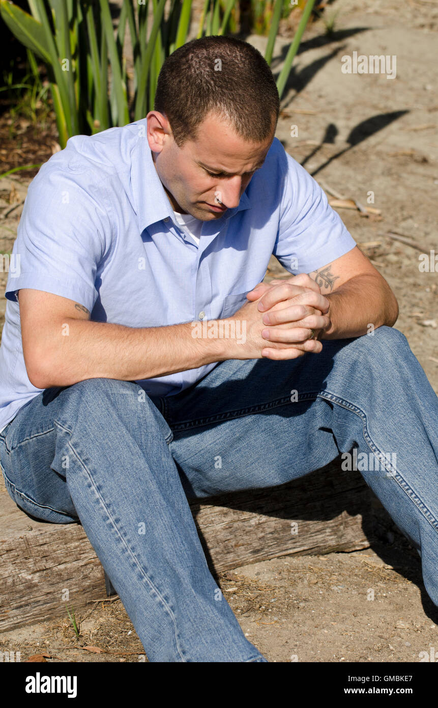 Man sitting and praying with hands folded and head bowed Stock Photo Alamy