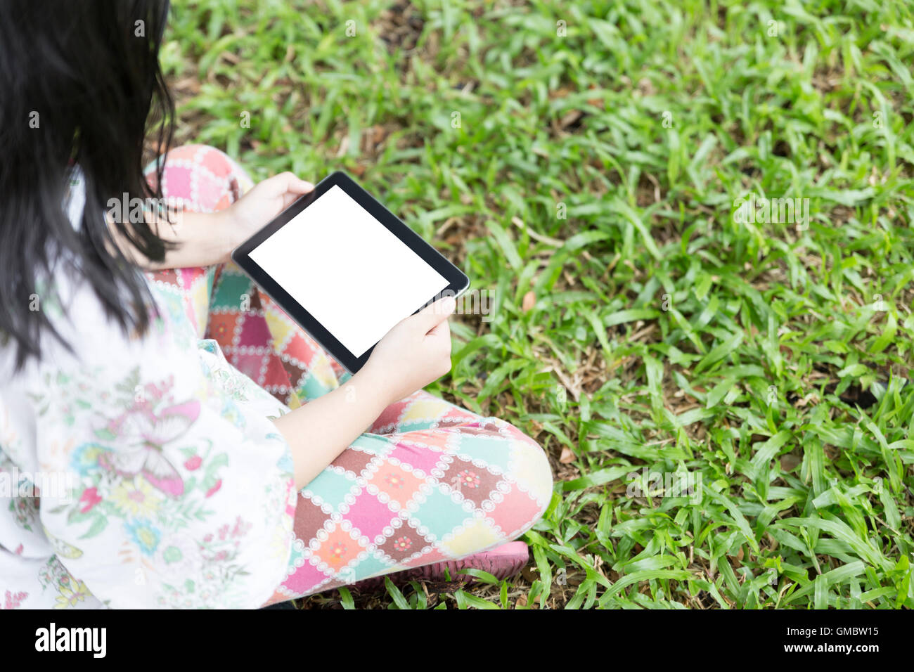 girl holding digital tablet sitting on grass lawn yard Stock Photo - Alamy