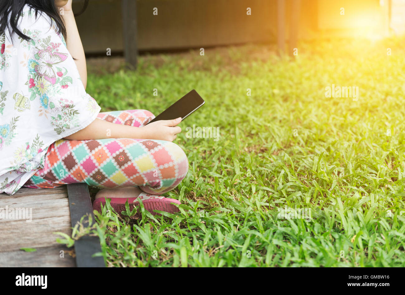 girl holding digital tablet sitting on grass lawn yard Stock Photo - Alamy