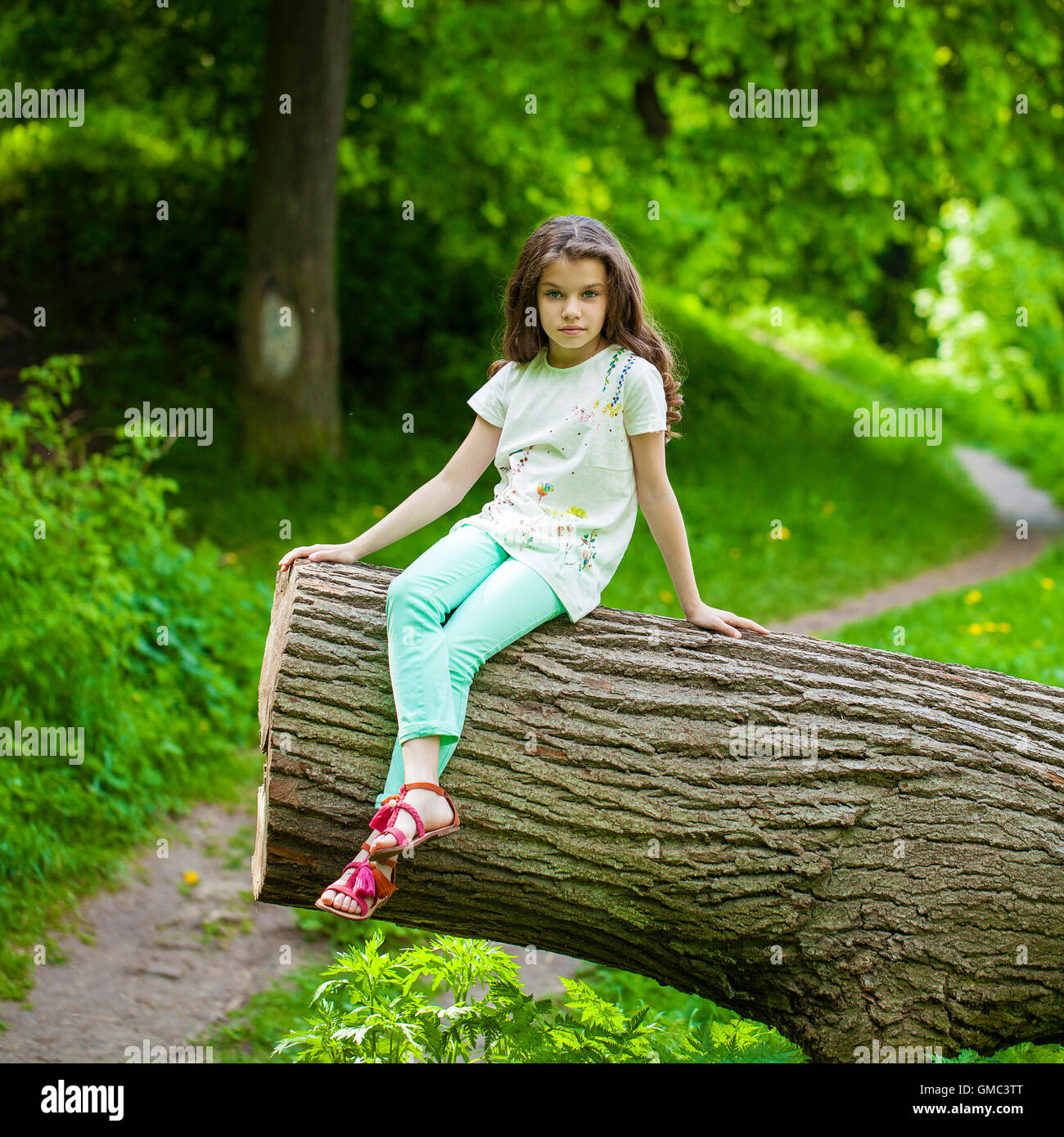 https://c8.alamy.com/comp/GMC3TT/little-girl-in-white-dress-sitting-on-tree-trunk-on-the-background-GMC3TT.jpg