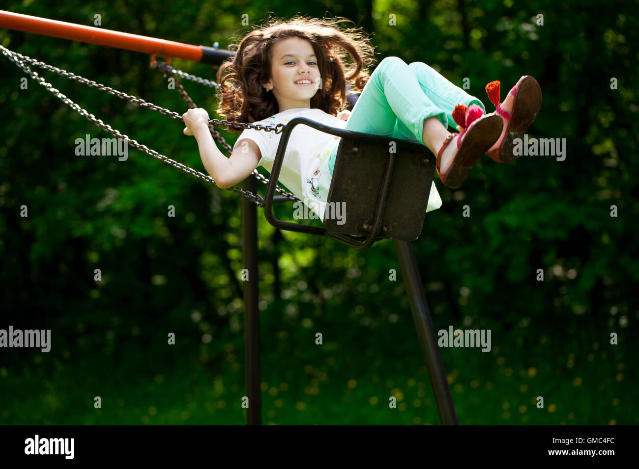 Happy Little girl on a swing in the summer park Stock Photo - Alamy