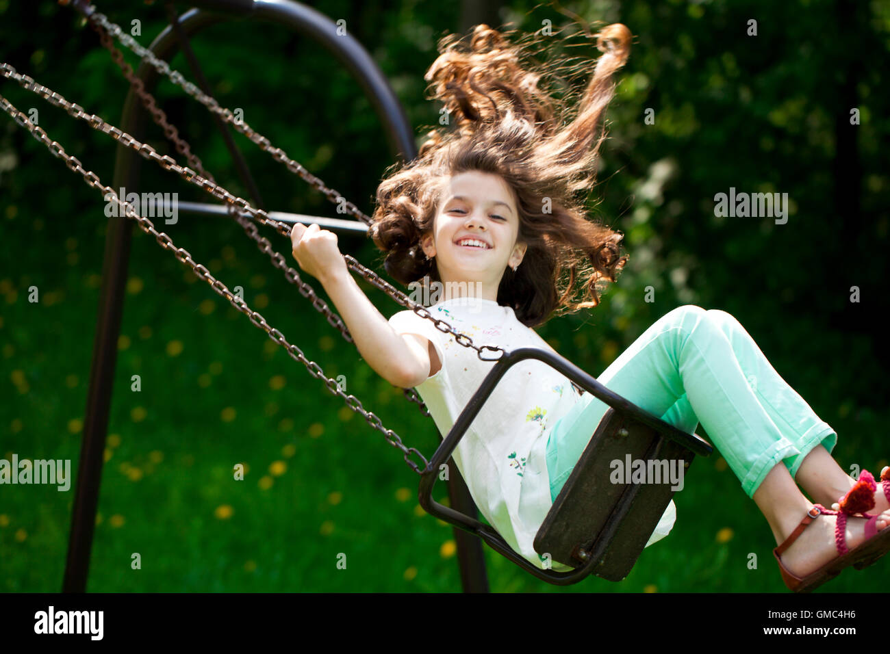Happy Little girl on a swing in the summer park Stock Photo - Alamy