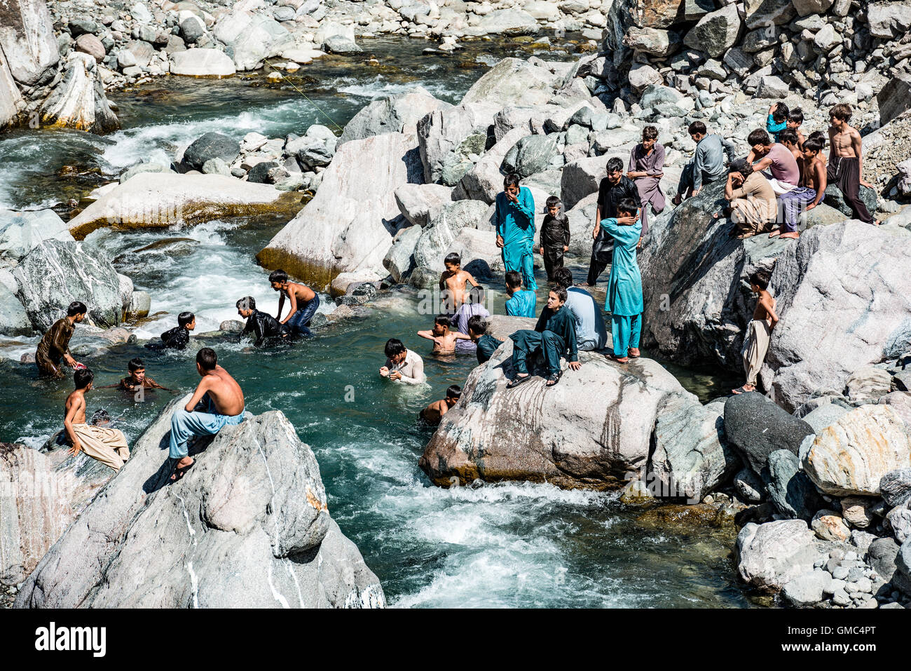 Boys sunbathing and swimming in a river in northern Pakistan Stock