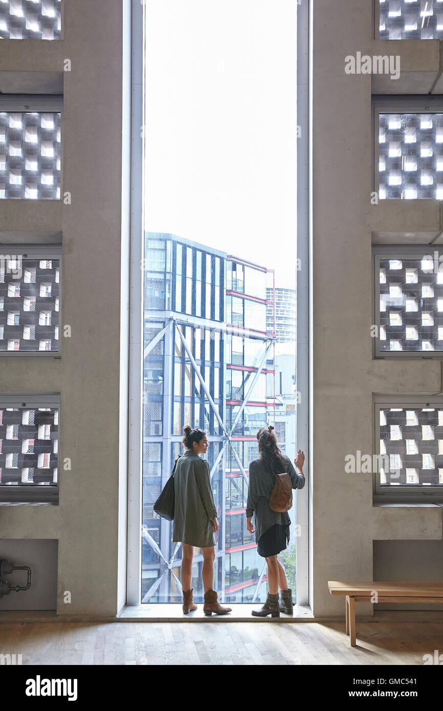 Two women look out over the city from a tall narrow window. SWITCH HOUSE AT TATE MODERN, London, United Kingdom. Architect: HERZOG & DE MEURON, 2016. Stock Photo