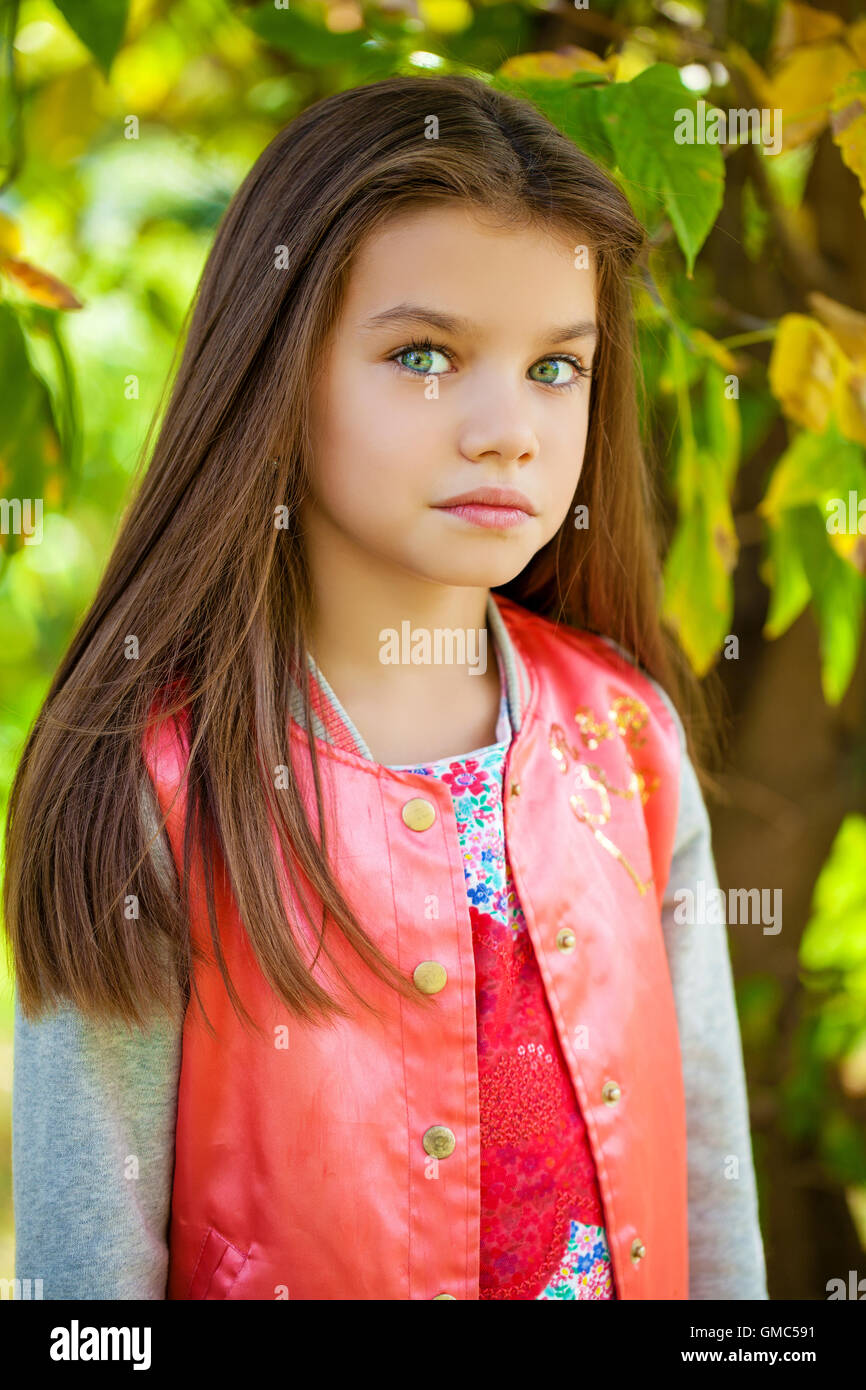 Cose up, Beautiful little girl on green background of summer city park Stock Photo