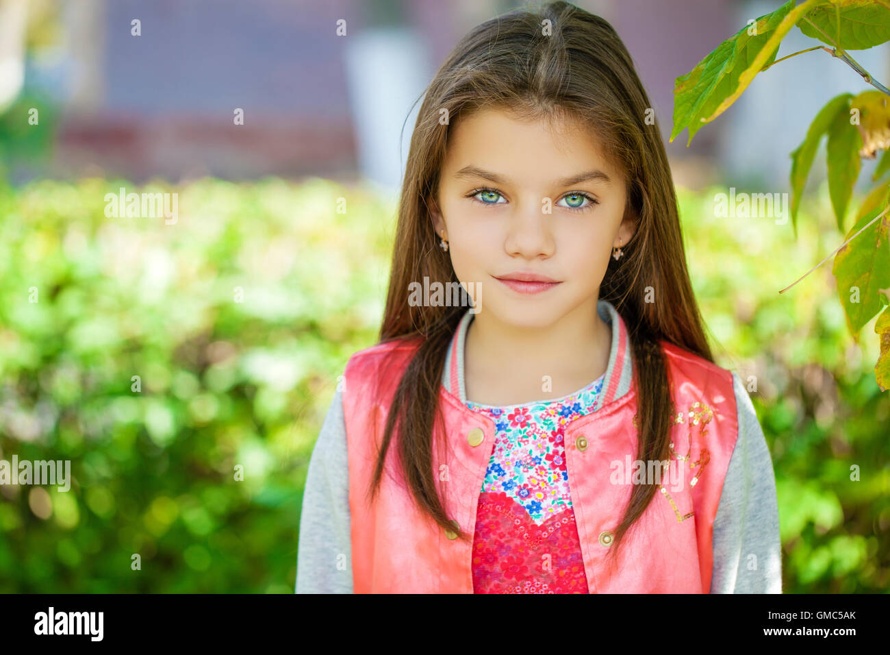 Cose up, Beautiful little girl on green background of summer city park Stock Photo