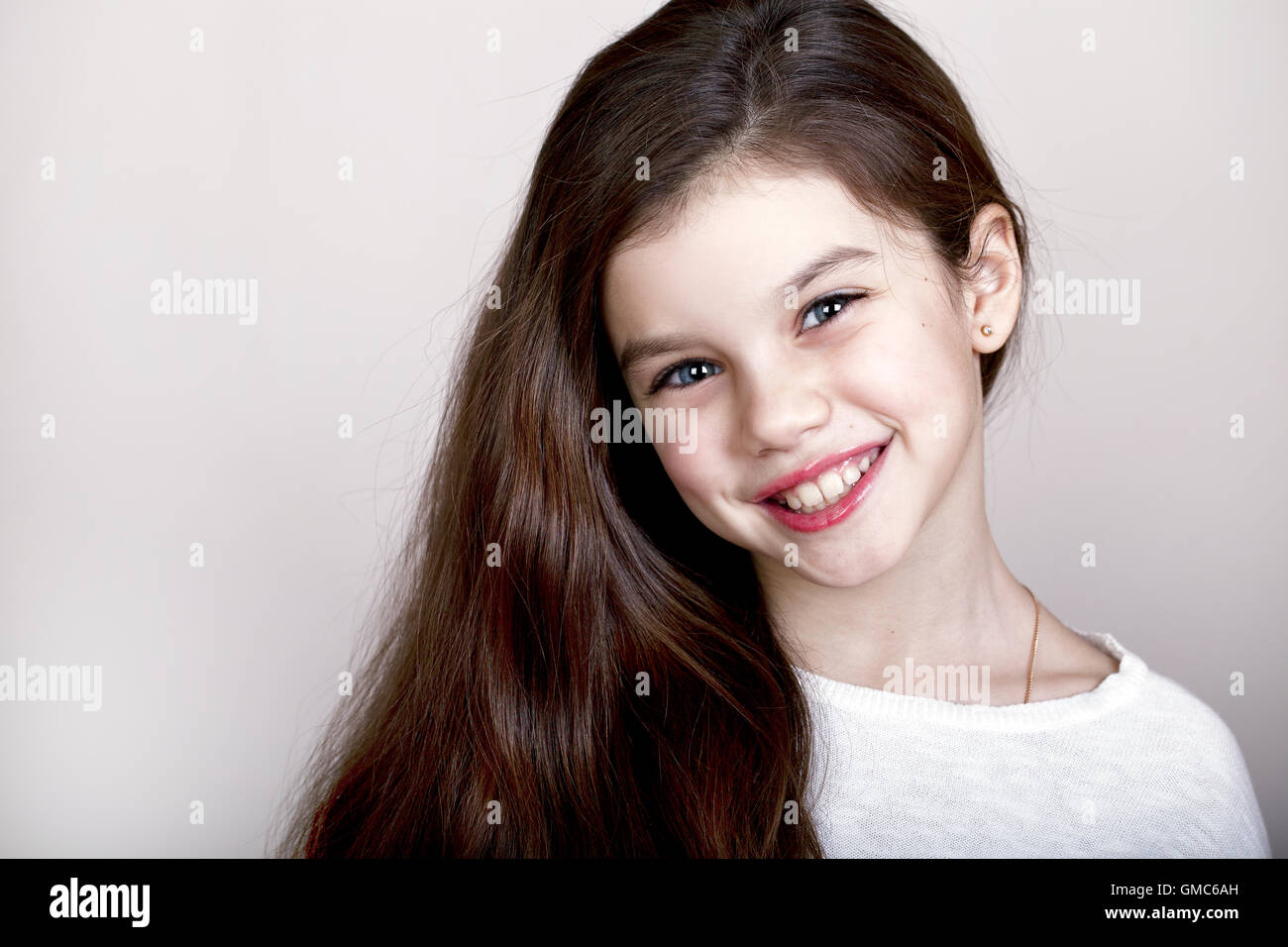 Portrait of a charming little girl smiling at camera, isolated on white ...