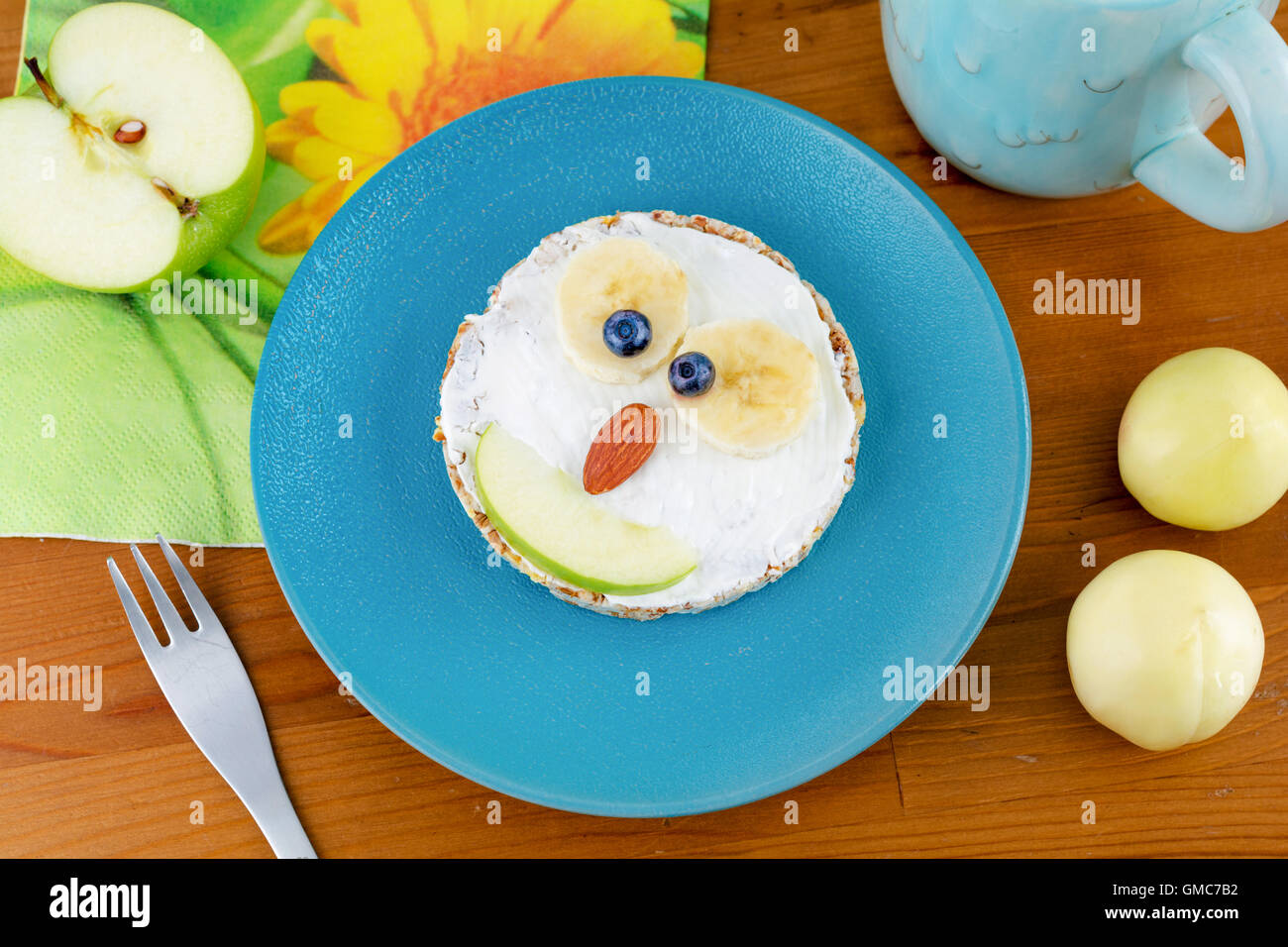 Animal face pancake for kids healthy breakfast on blue plate, top view. Funny children meal for breakfast. Owl shaped Stock Photo