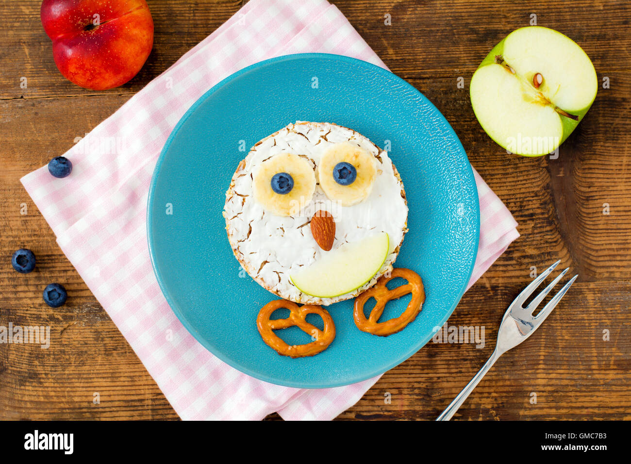 Creative healthy breakfast for children: rice crisp bread with cream cheese, fruits and nuts shaped as funny hen Stock Photo