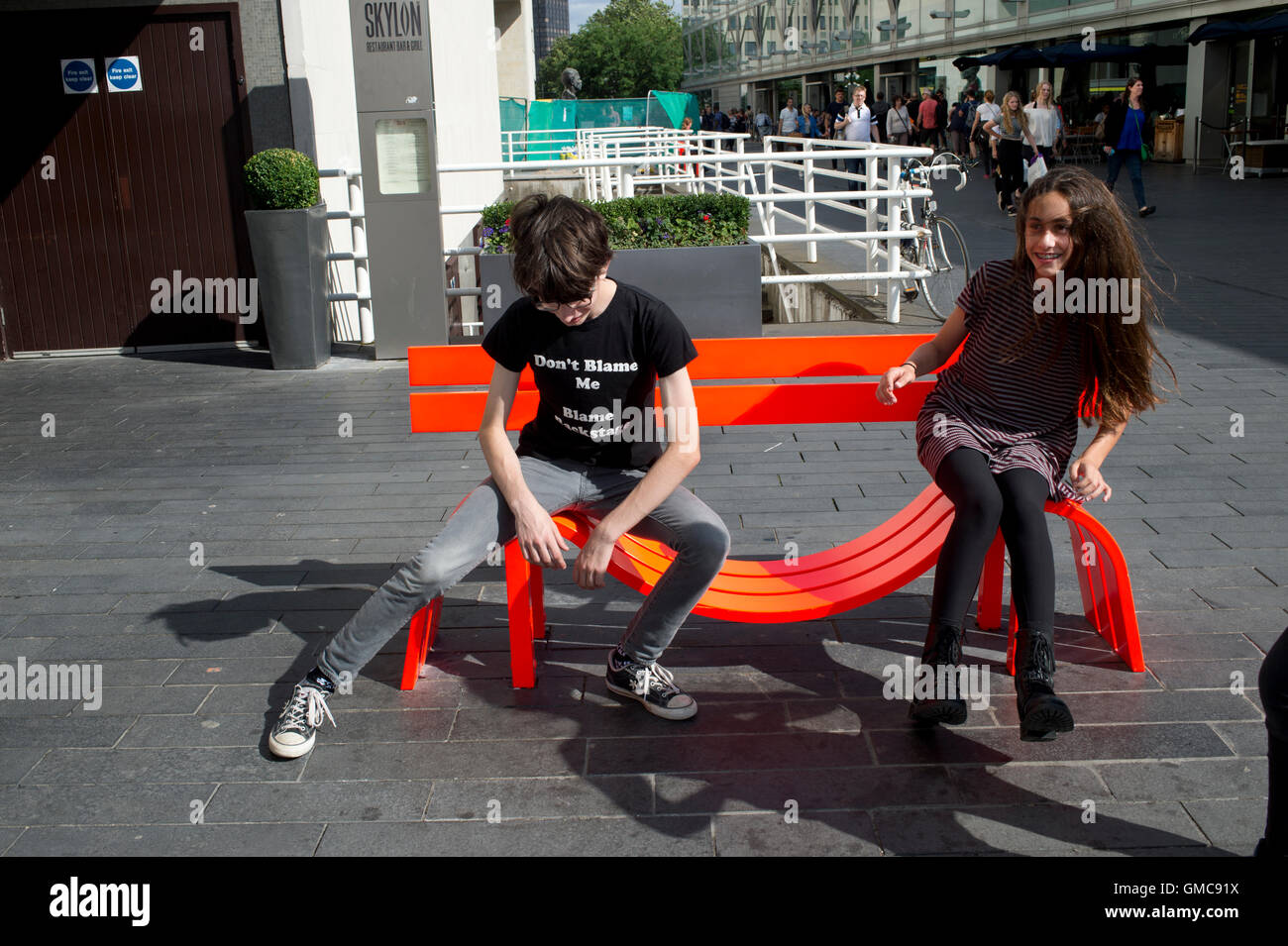 London.South Bank. Modified social bench NY. A young boy and girl play on Jeppe Hein's reinvention of the park bench Stock Photo
