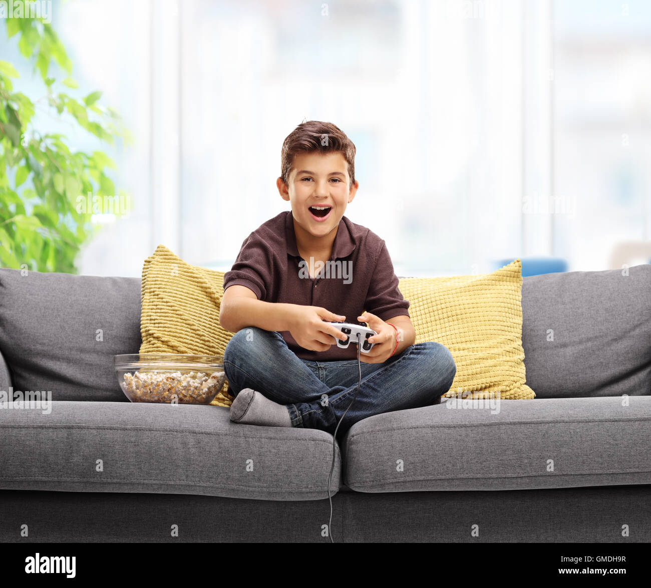 Happy kid playing video games and sitting on a sofa Stock Photo Alamy