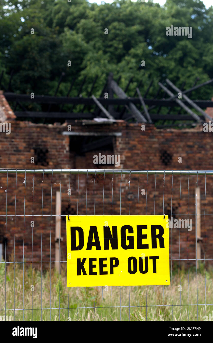 Fire damage to old farm building. Danger keep out sign. Stock Photo