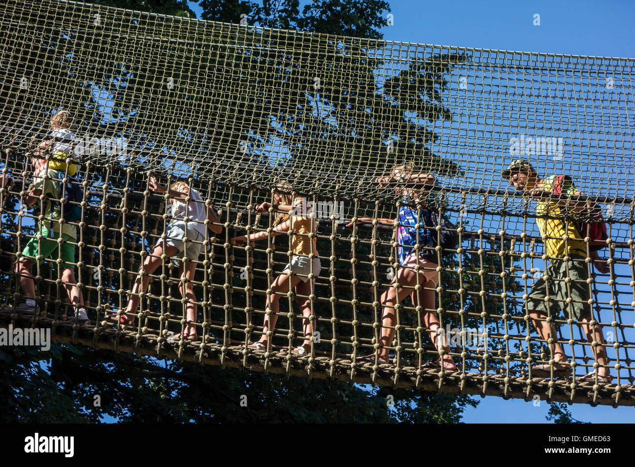 Parents with kids walking over rope bridge / swing bridge / suspended