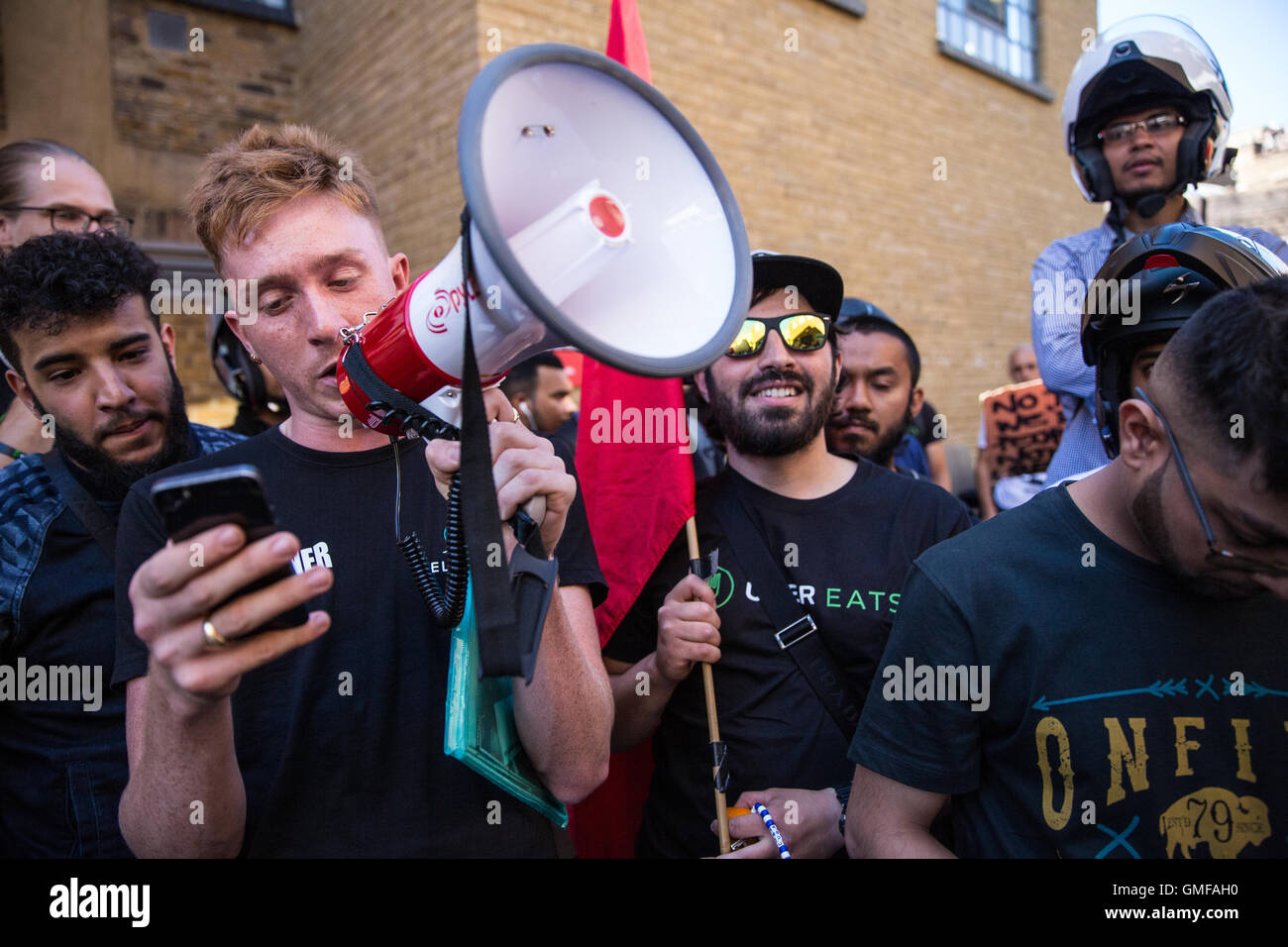 London, UK. 26th August, 2016.  Ben Geraghty, Deliveroo courier, reads aloud the demands of UberEats couriers outside the company's headquarters in Bermondsey during a protest against cuts to their pay at the beginning of a strike. Credit:  Mark Kerrison/Alamy Live News Stock Photo