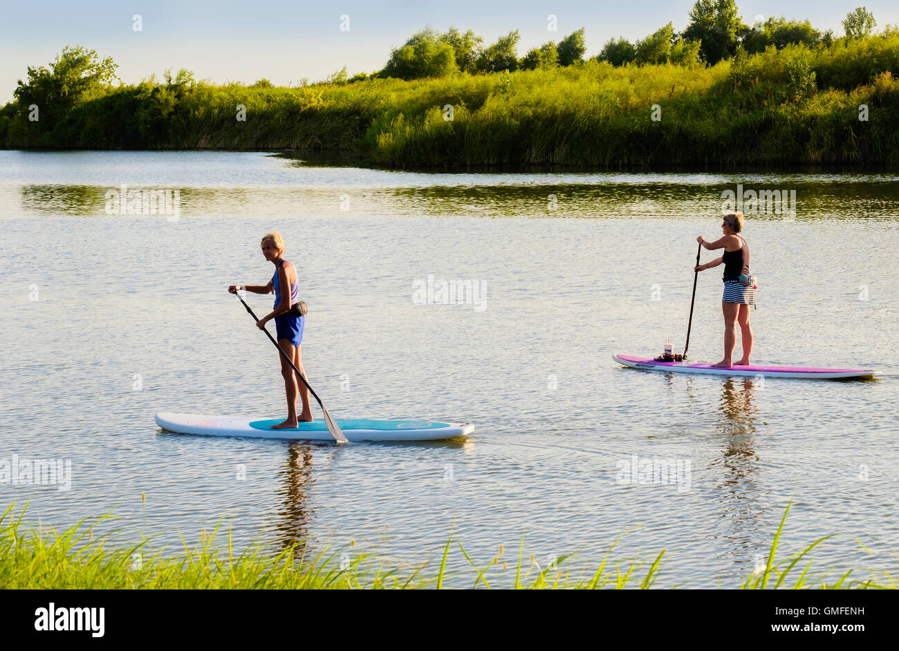Two middle aged Caucasian women on stand up paddleboards on the North Canadian river, Oklahoma, USA. Stock Photo