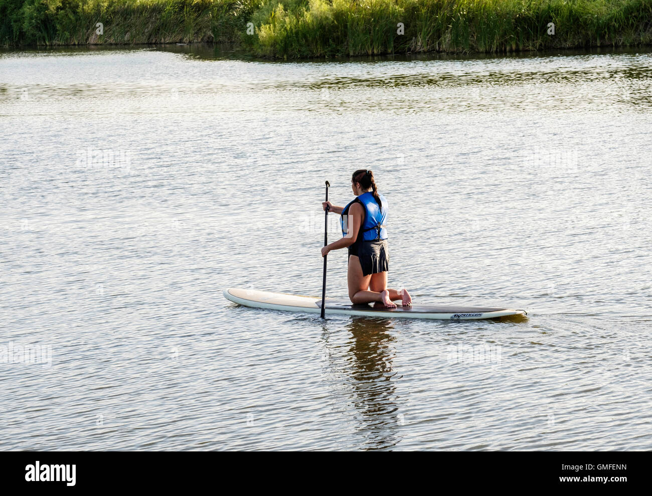 A Caucasian woman kneels and paddles on a paddleboard on the North Canadian river near Overholser lake in Oklahoma, USA. Stock Photo