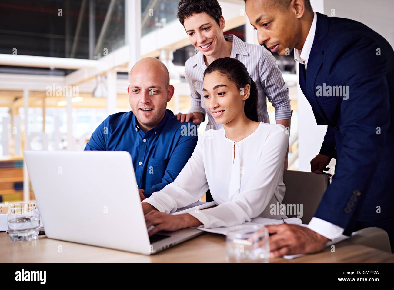 four well dressed diverse entrepreneurs looking at a laptop screen Stock Photo