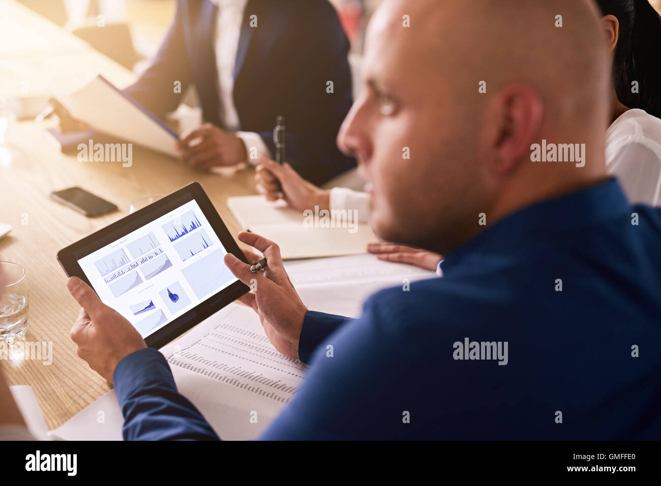 tablet in a business meeting with graphs on the screen Stock Photo