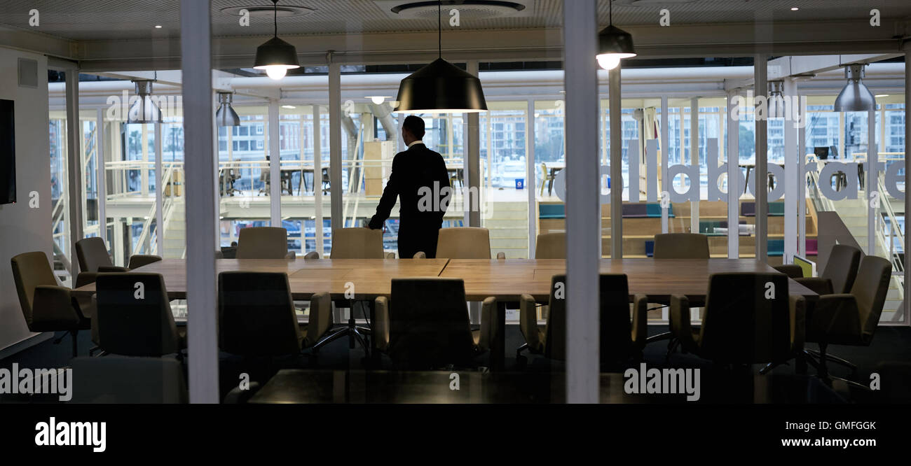 Aspirational businessman standing in empty conference room looking out window Stock Photo