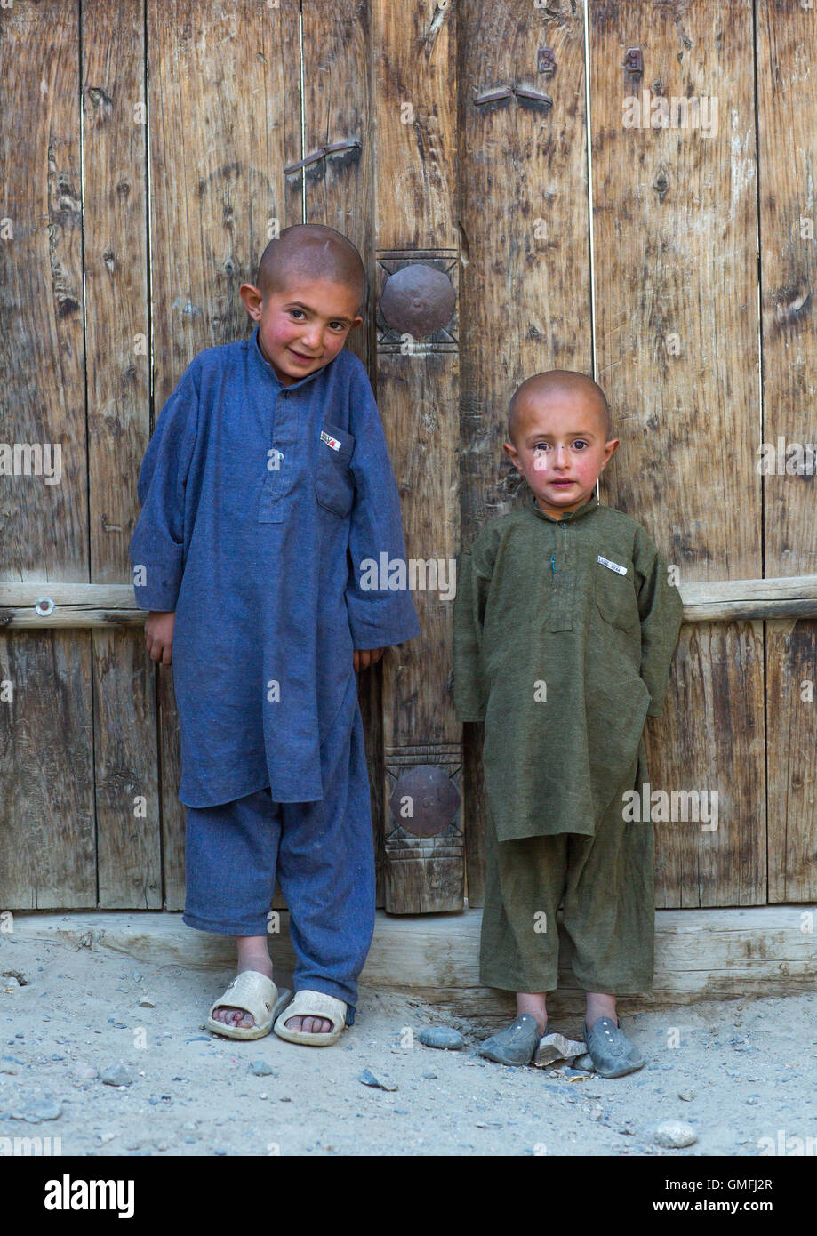 Afghan boys with shaved heads standing in front of a wooden door, Badakhshan province, Khandood, Afghanistan Stock Photo