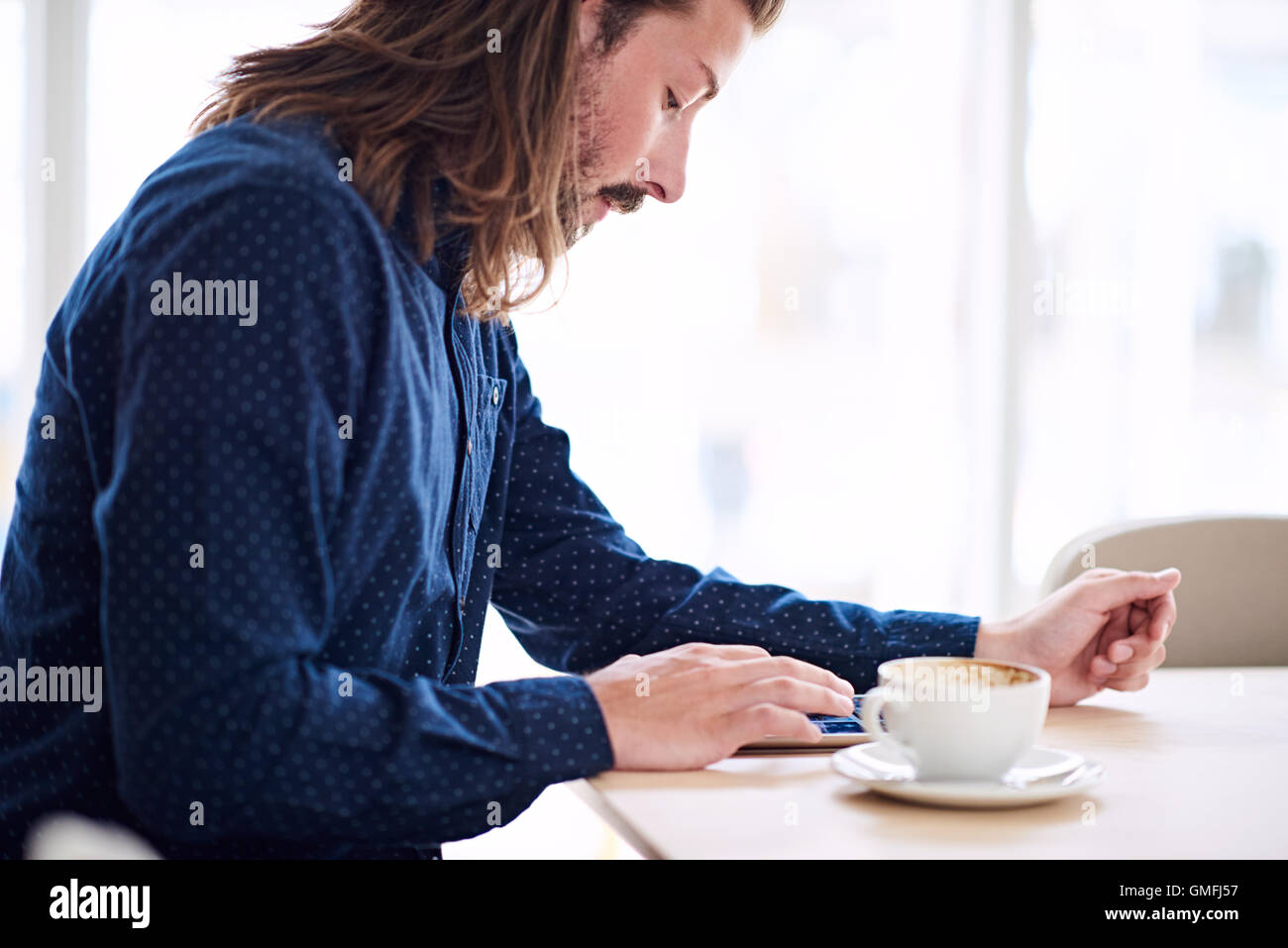 Trendy male hipster busy using his tablet on the table Stock Photo