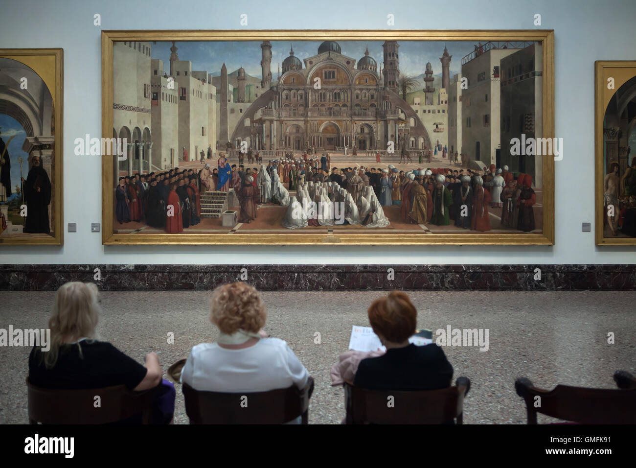 Visitors in front of the painting 'Saint Mark preaching in Alexandria' (1504-1507) by Venetian Renaissance painters Gentile and Giovanni Bellini displayed in the Pinacoteca di Brera in Milan, Lombardy, Italy. Stock Photo