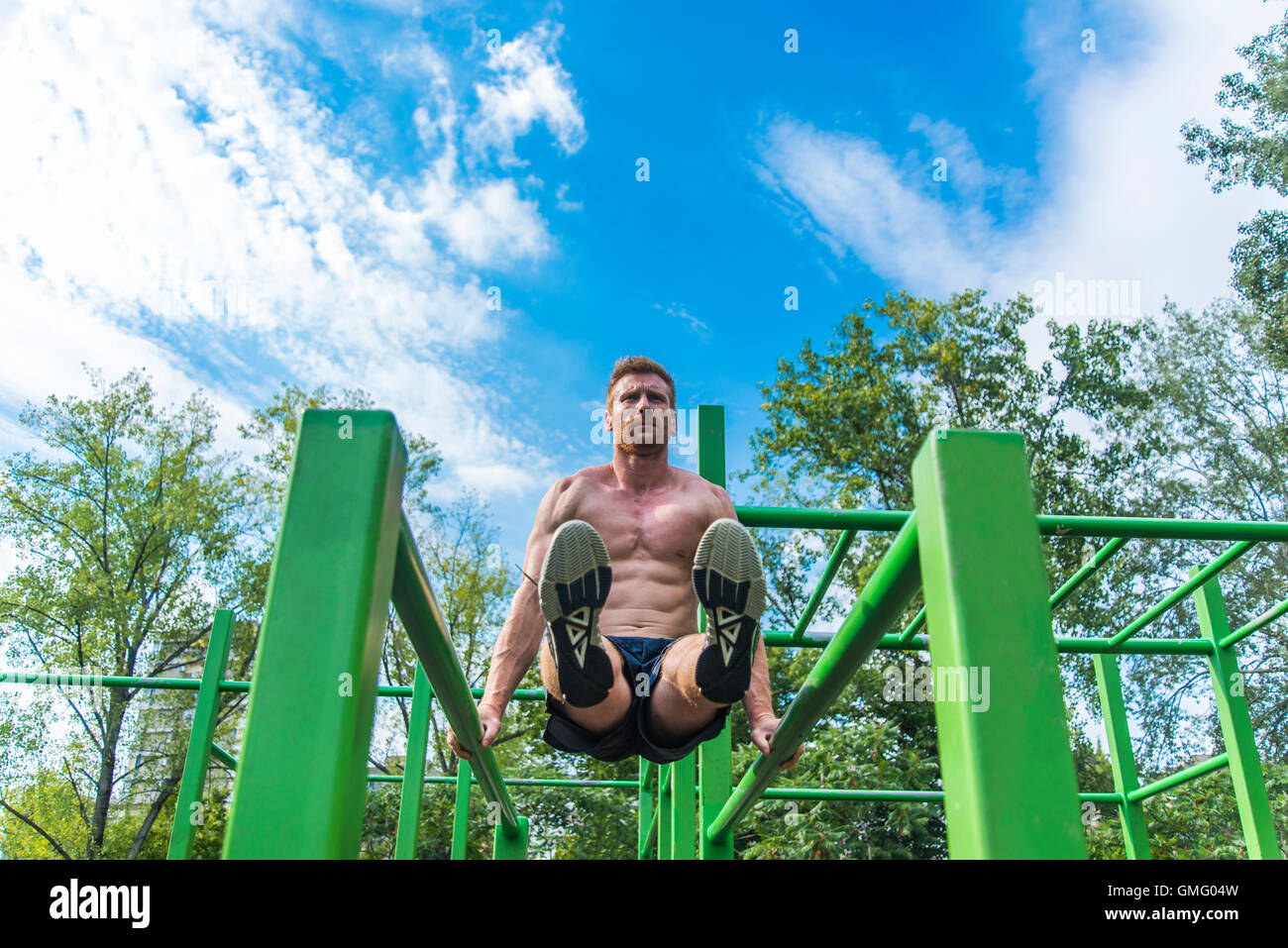Young man doing pull ups on horizontal bar outdoors Stock Photo - Alamy