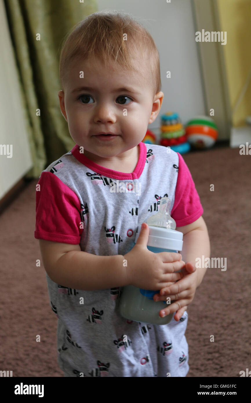 closeup portrait of a baby girl holding bottle with milk. vertical Stock Photo
