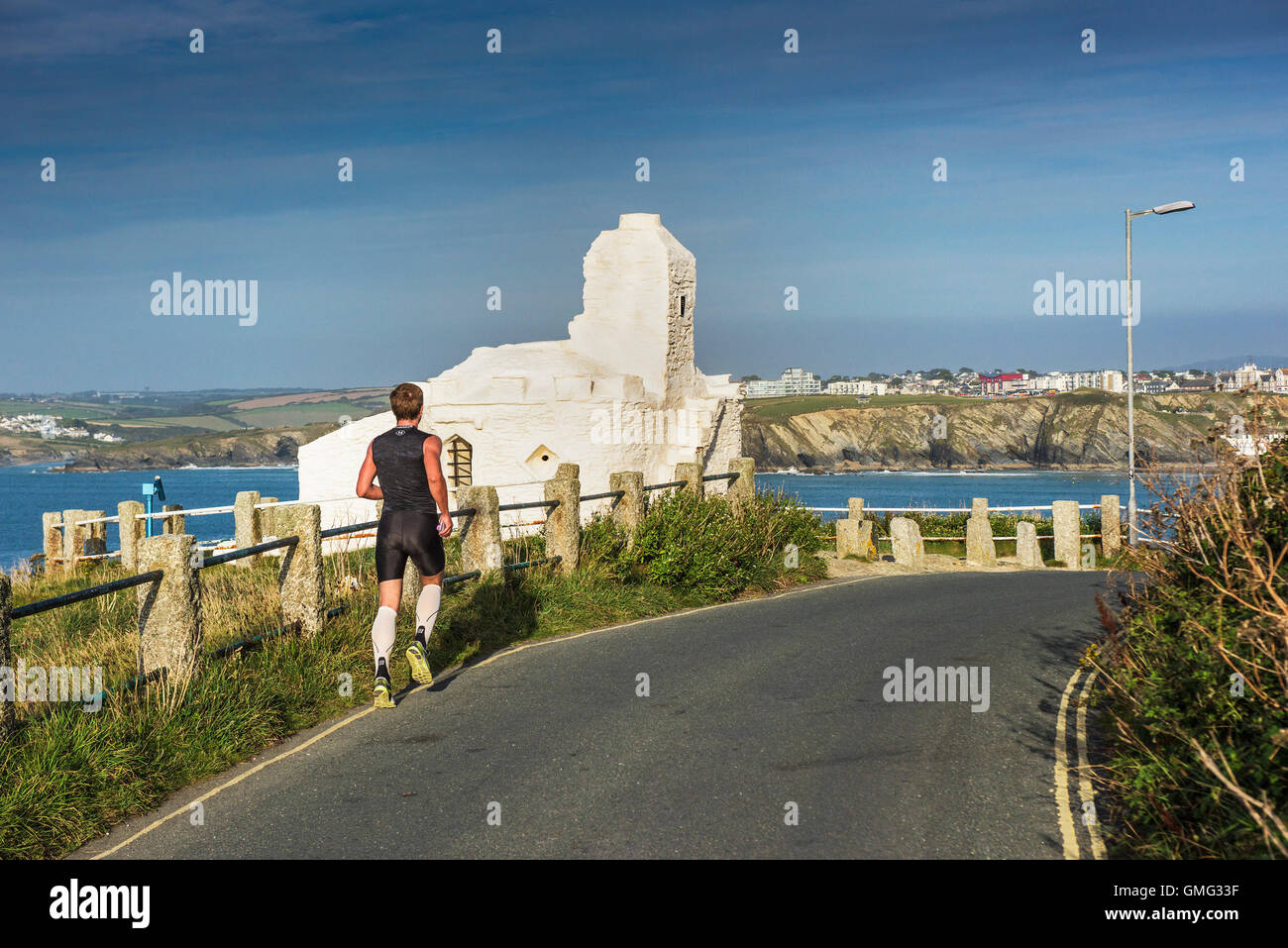 A jogger runs past the Grade II listed Huer’s Hut on the coast of Newquay in Cornwall. Stock Photo