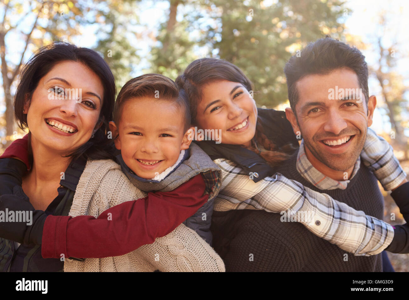 Portrait of happy parents piggybacking kids outdoors Stock Photo