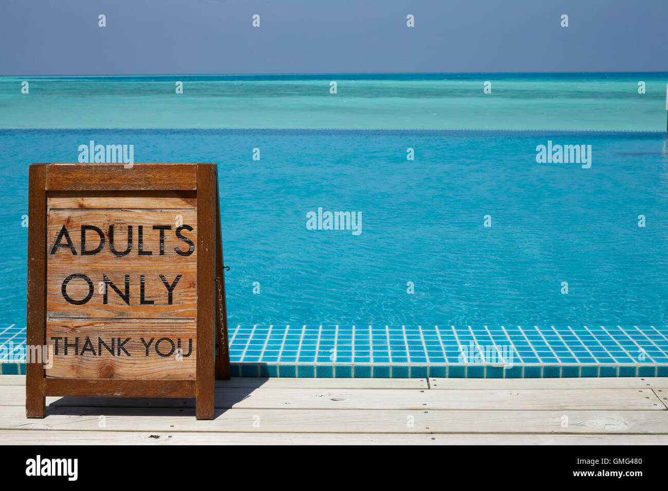 Adults only sign by an infinity pool with ocean beyond Stock Photo
