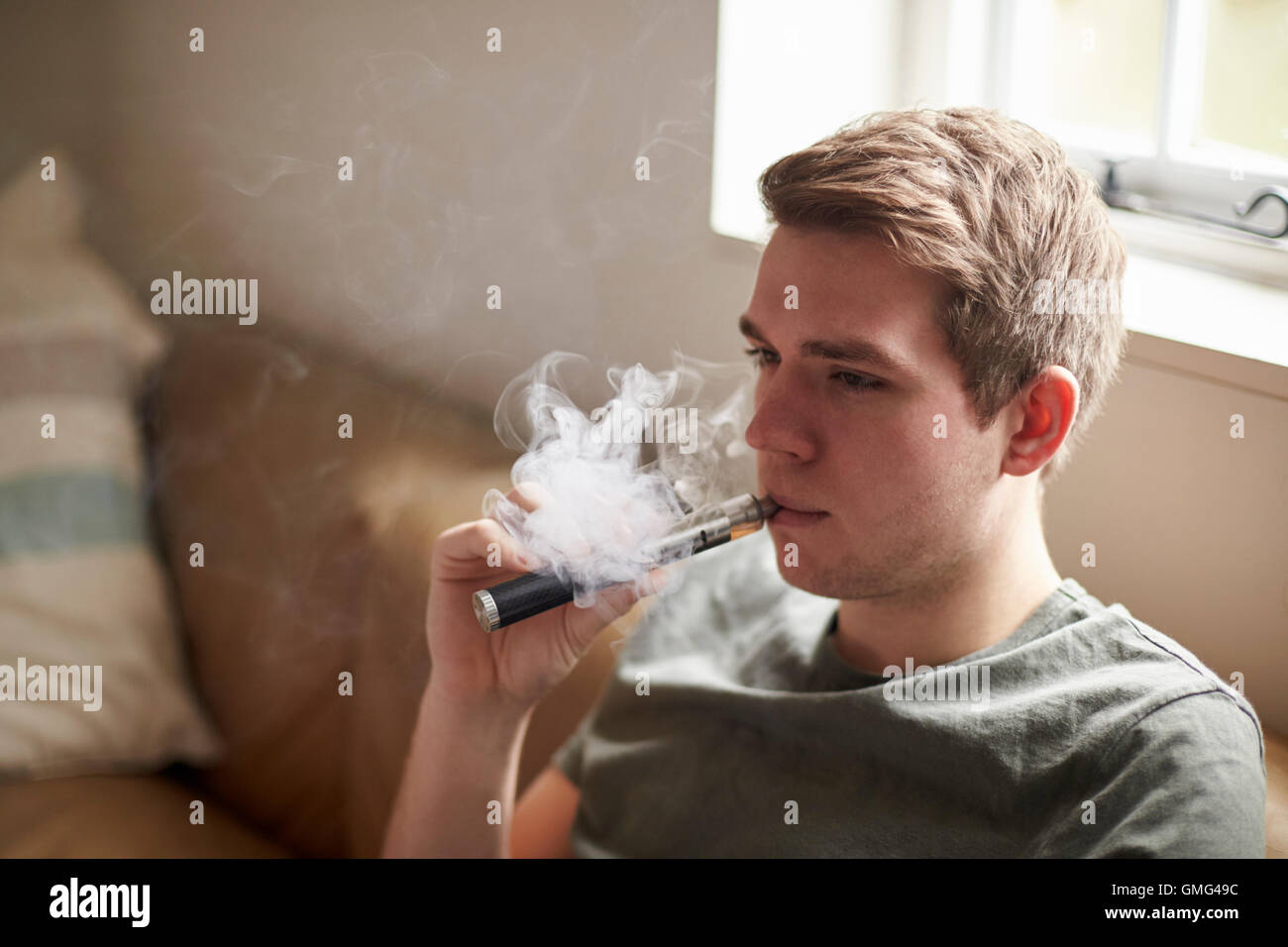 Young Man Using Vapourizer As Smoking Alternative Stock Photo
