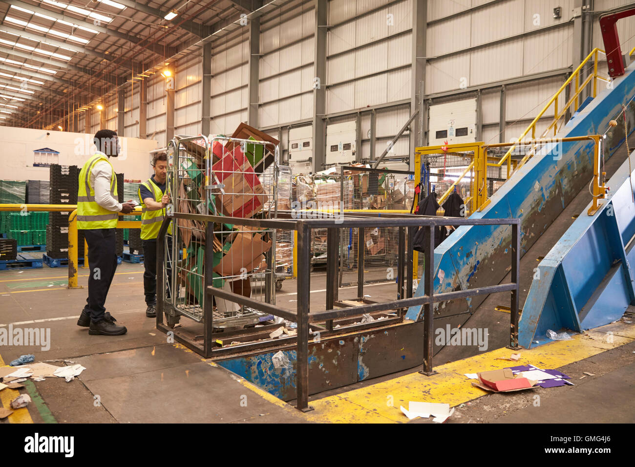 Warehouse staff with a roll cage of cardboard for recycling Stock Photo