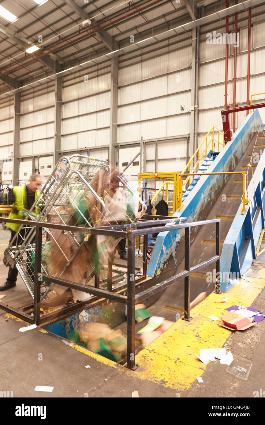 A roll cage of cardboard is emptied into recycling machinery Stock Photo Alamy