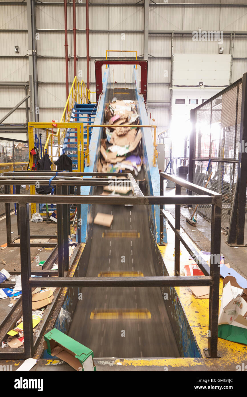 Cardboard travelling up conveyor belt of recycling machinery Stock
