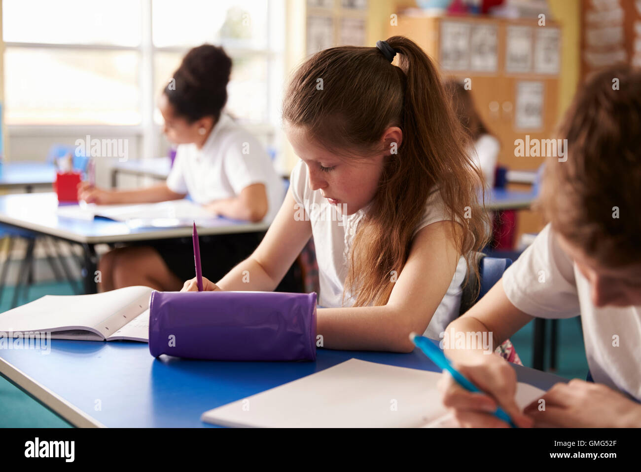 Two kids working at their desks in primary school, crop shot Stock ...