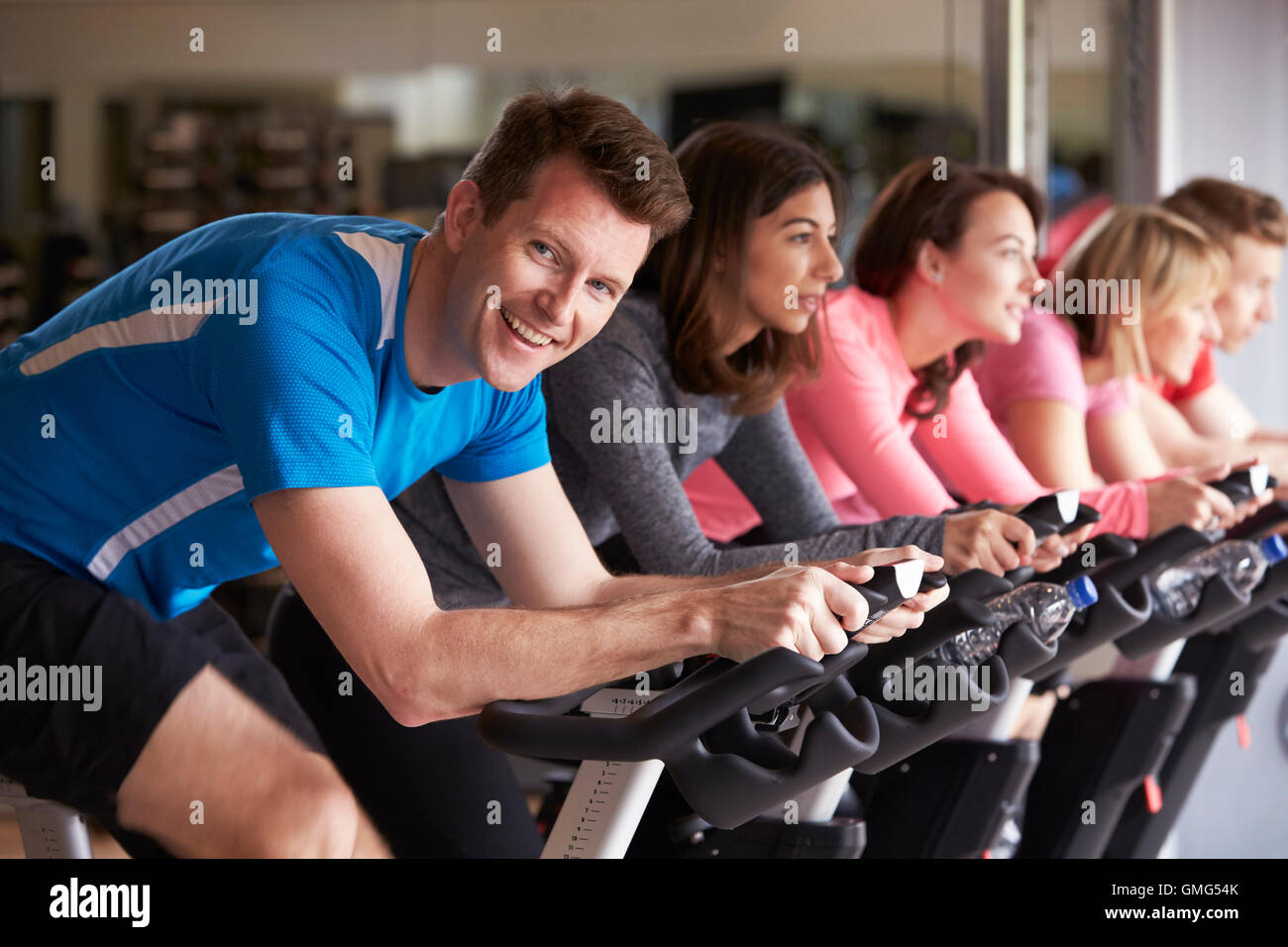 Man in a spinning class at a gym turning to smile at camera Stock Photo ...