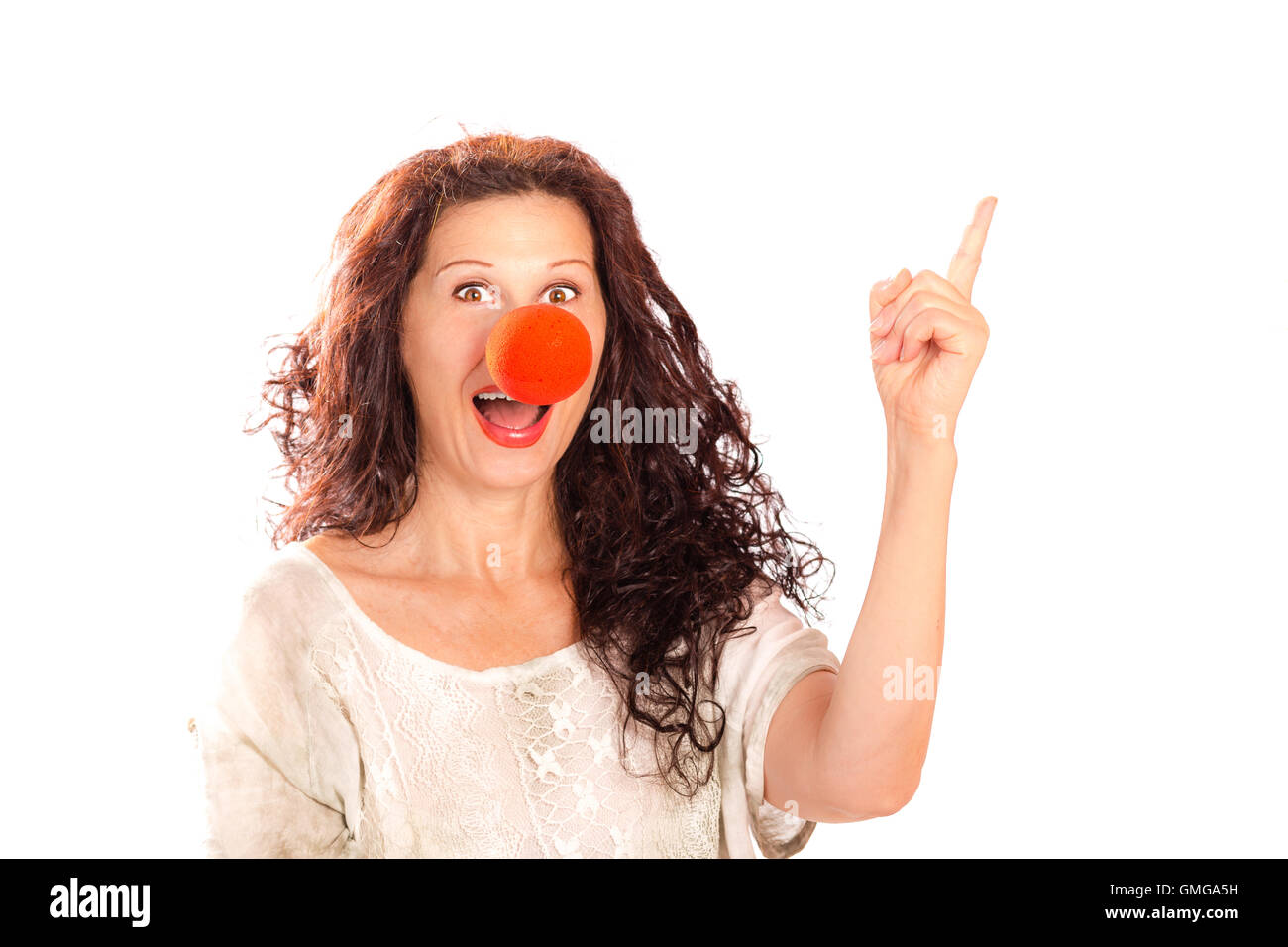 Portrait of a senior woman with red clown nose pointing finger away isolated on white Stock Photo
