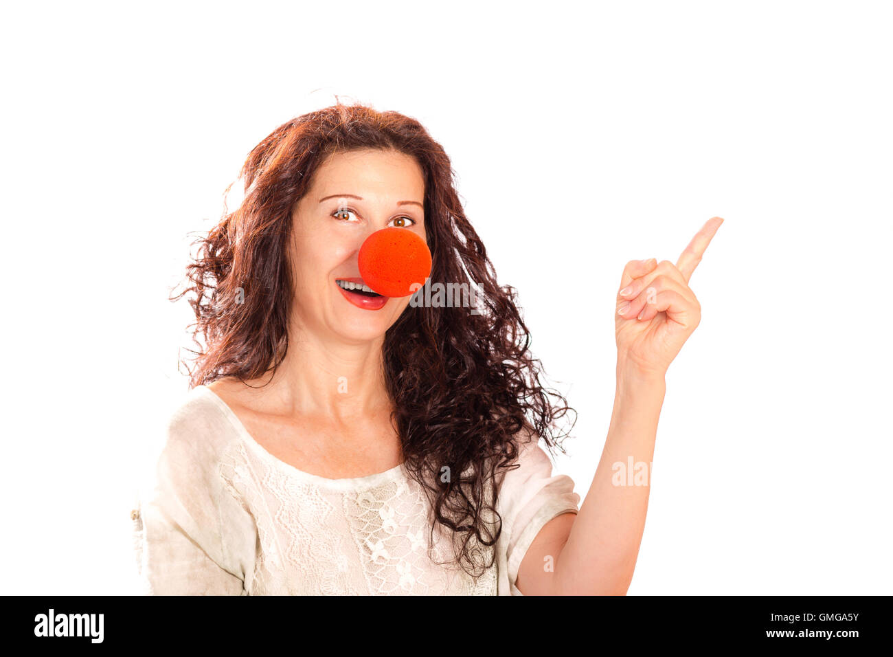 Portrait of a senior woman with red clown nose pointing finger away isolated on white Stock Photo