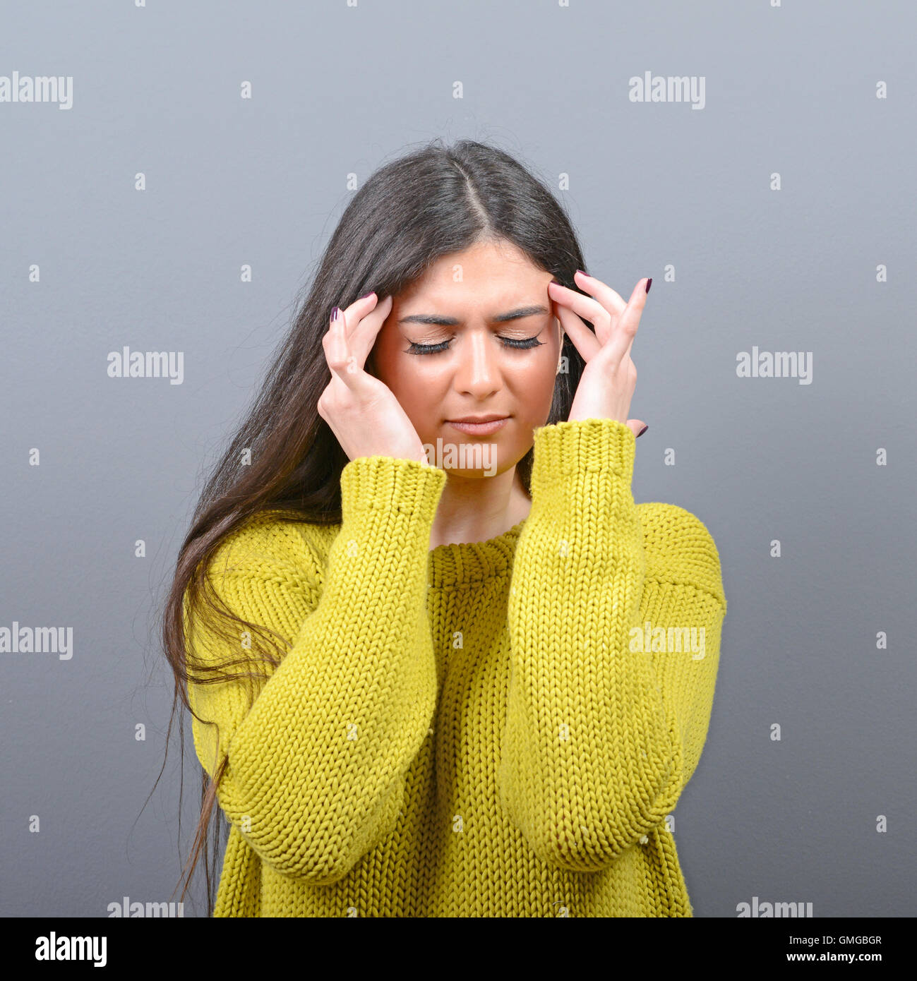 Portrait of woman concentrating against gray background Stock Photo