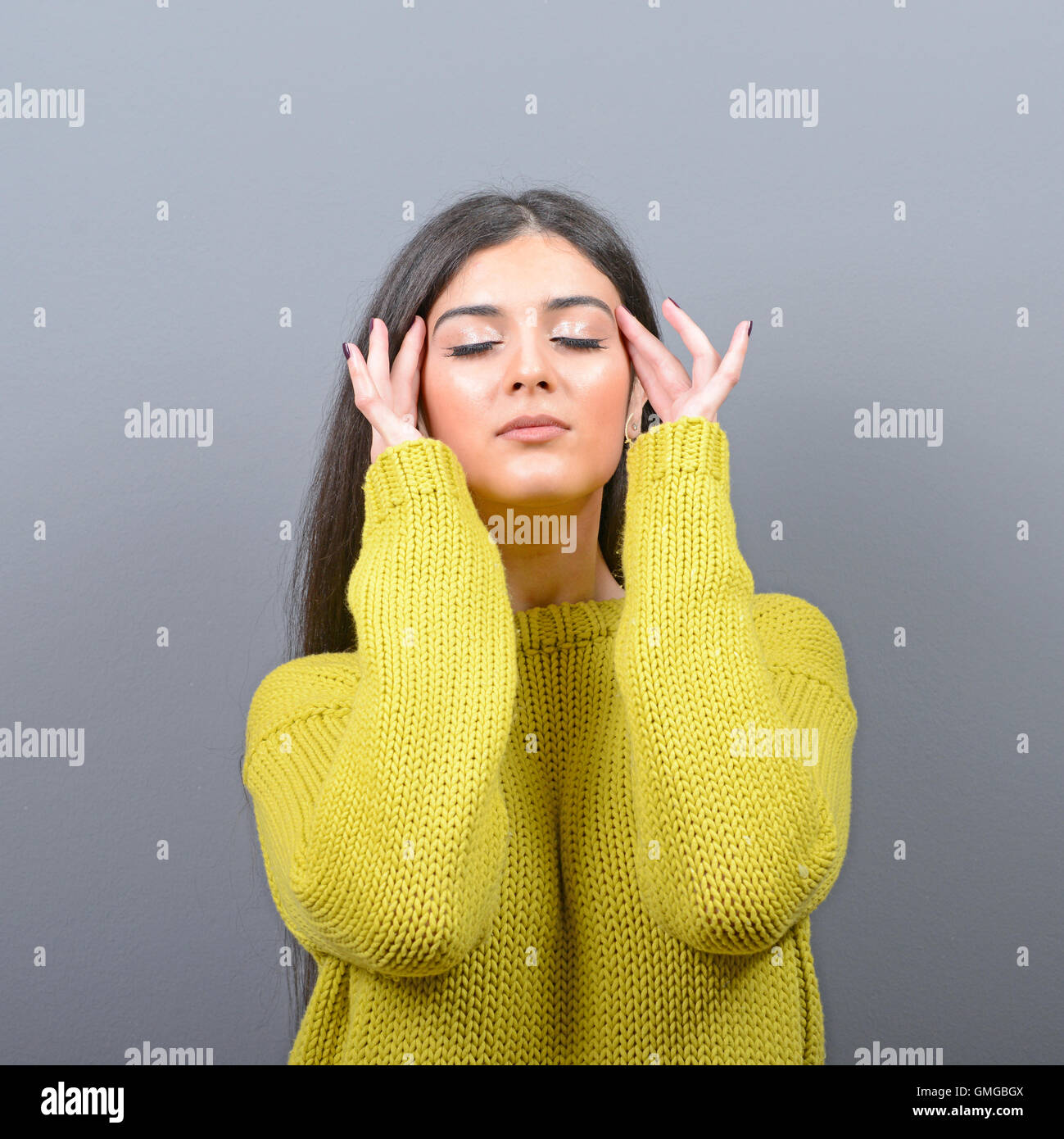 Portrait of woman concentrating against gray background Stock Photo