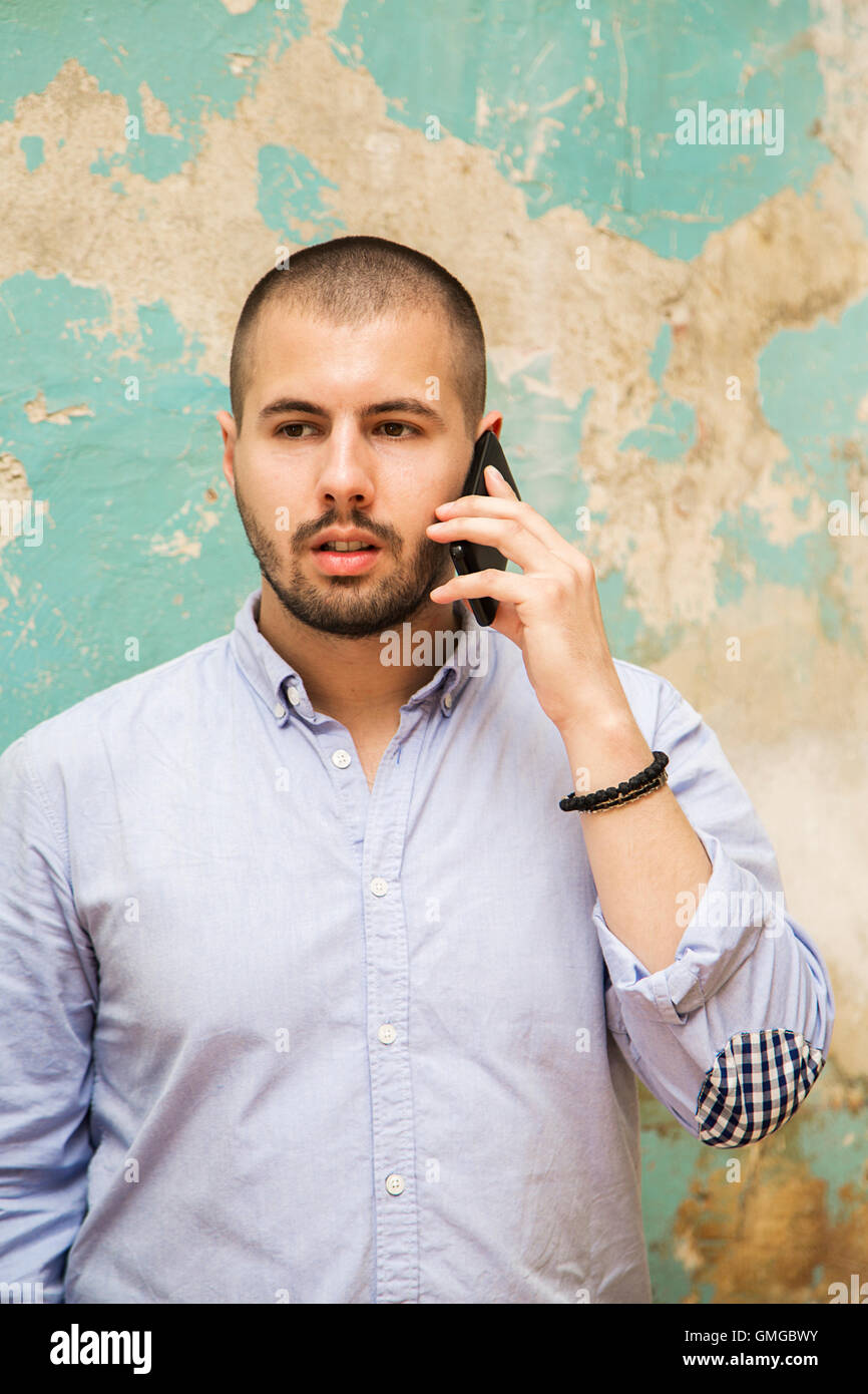 Young man using a telephone by old grunge wall Stock Photo