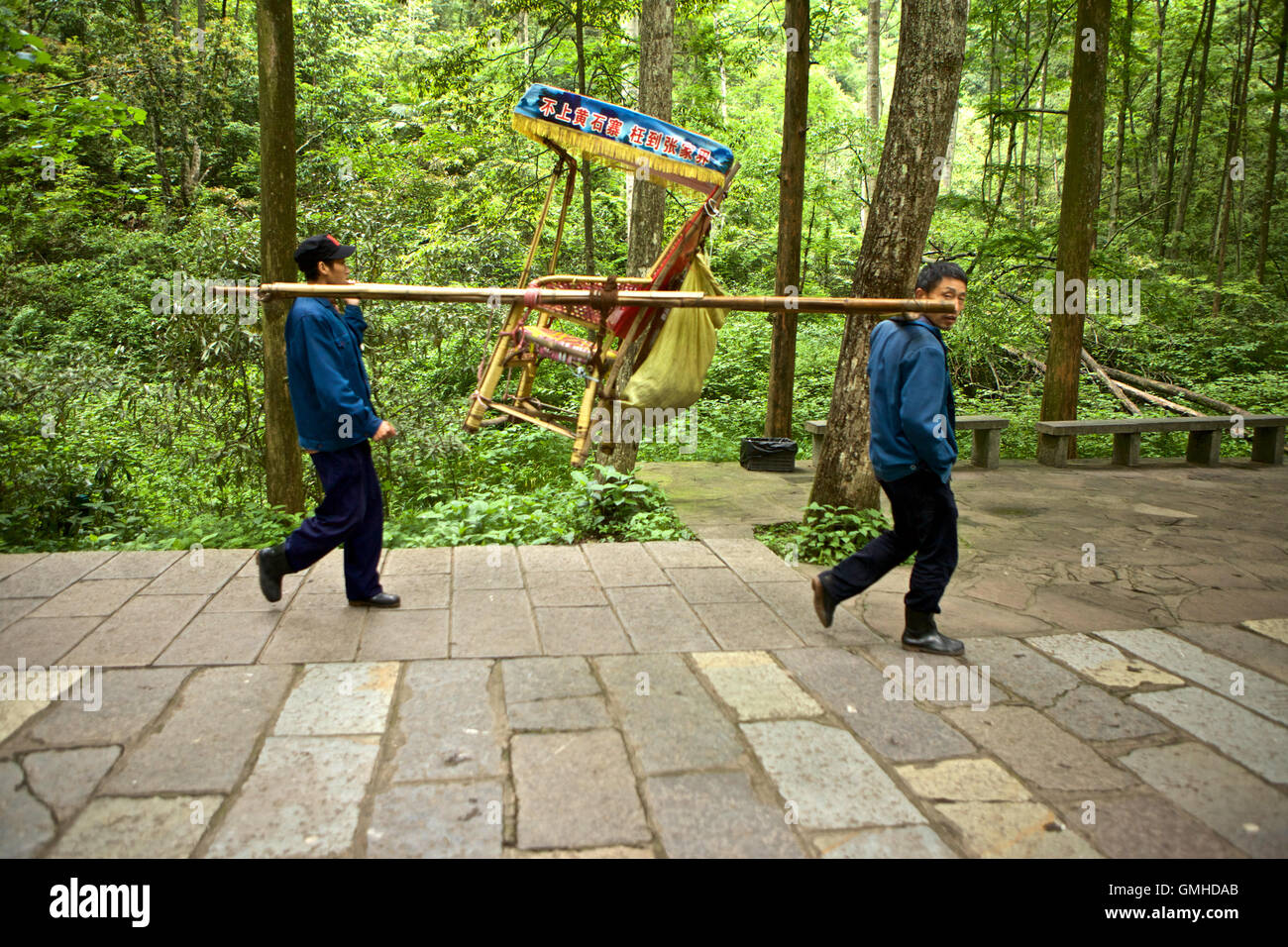 Two men holding an empty chair for transporting people at Zhangjiajie National Forest Park, Hunan  China Stock Photo